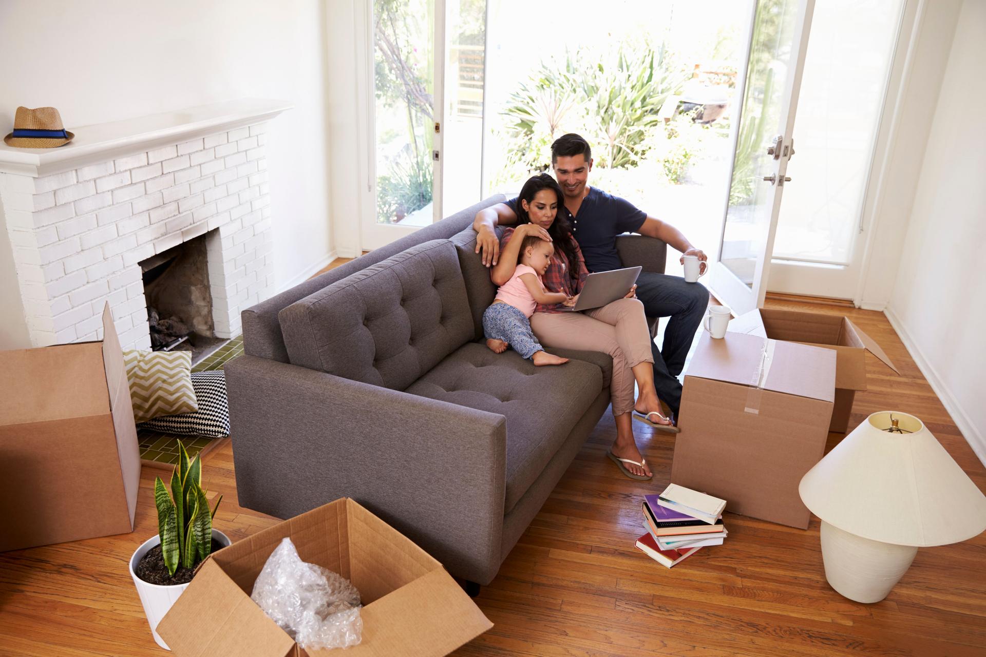 Family Take A Break On Sofa Using Laptop On Moving Day